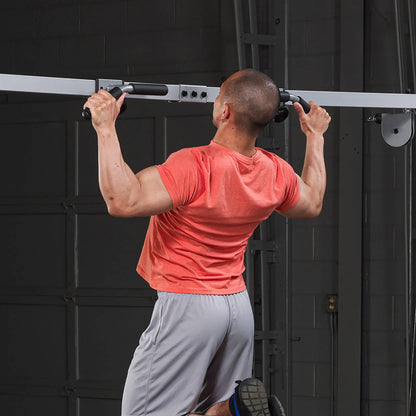 Man in red shirt doing pull-ups on a home gym pull-up bar.