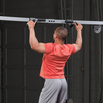 Man in red shirt doing pull-ups on a black pull-up bar in a garage gym.