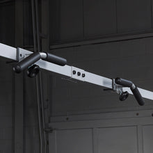 Ceiling-mounted pull-up bar with black foam grips in a gym setting.