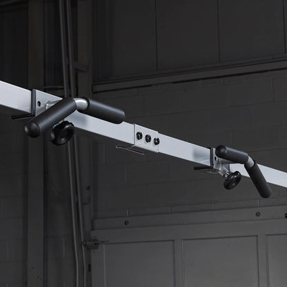Ceiling-mounted pull-up bar with black foam grips in a gym setting.