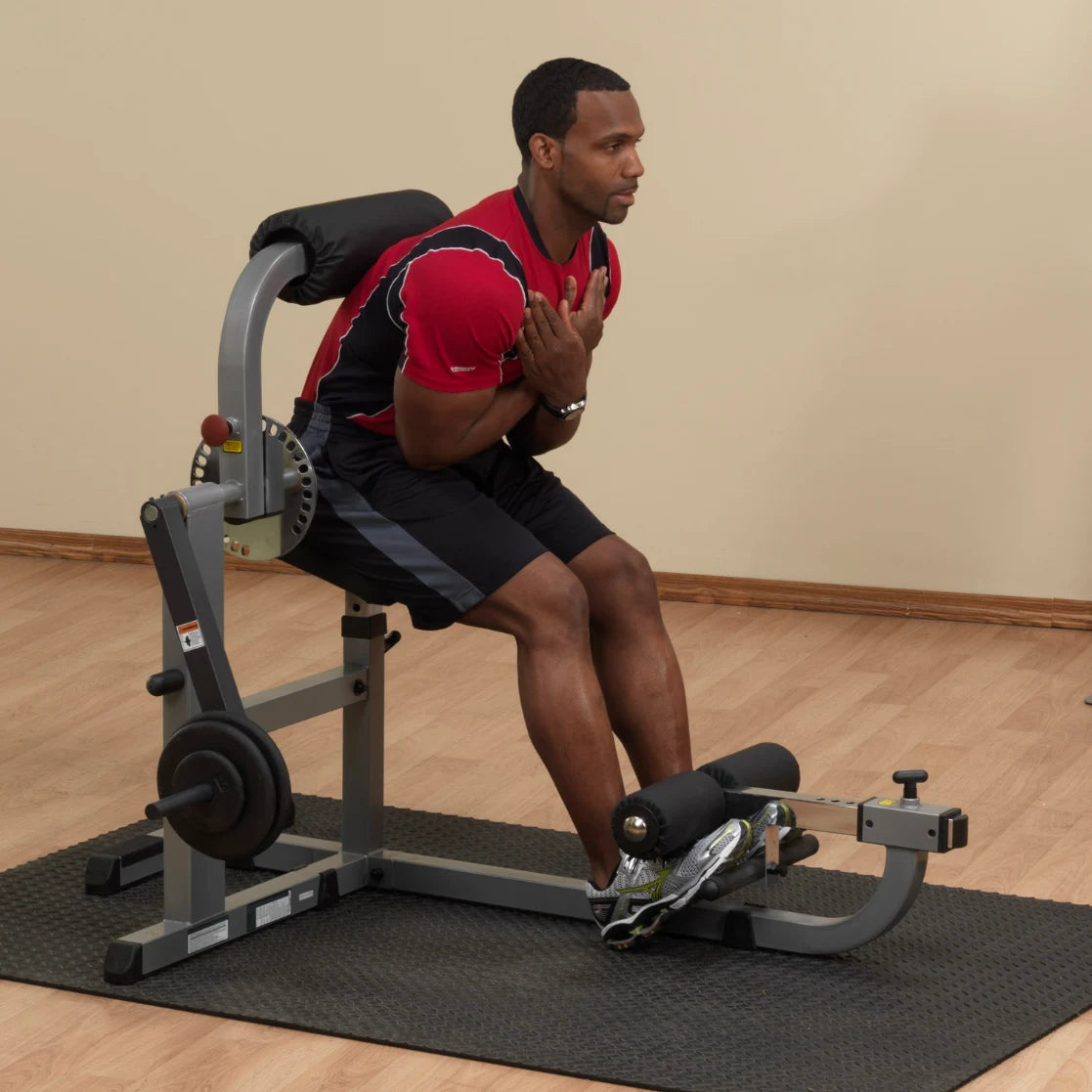 Man exercising on Powerline back extension machine in a red shirt.