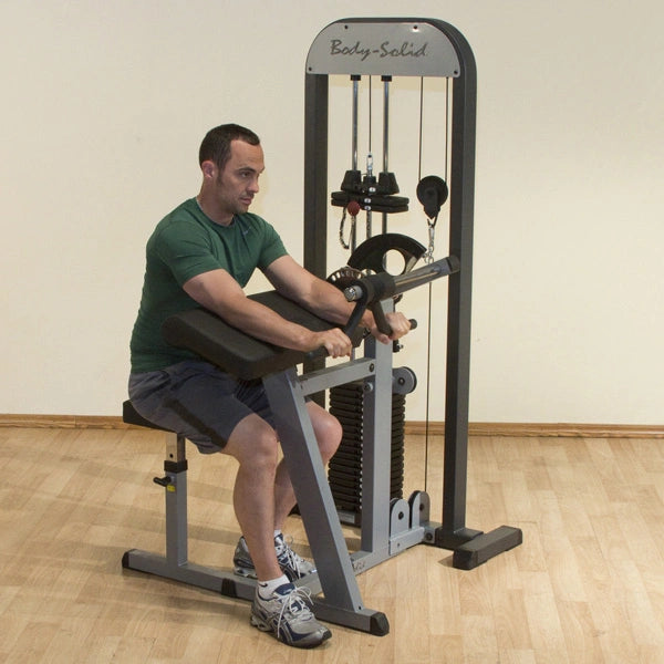 Man using Body-Solid bicep curl machine with adjustable weights in a gym.