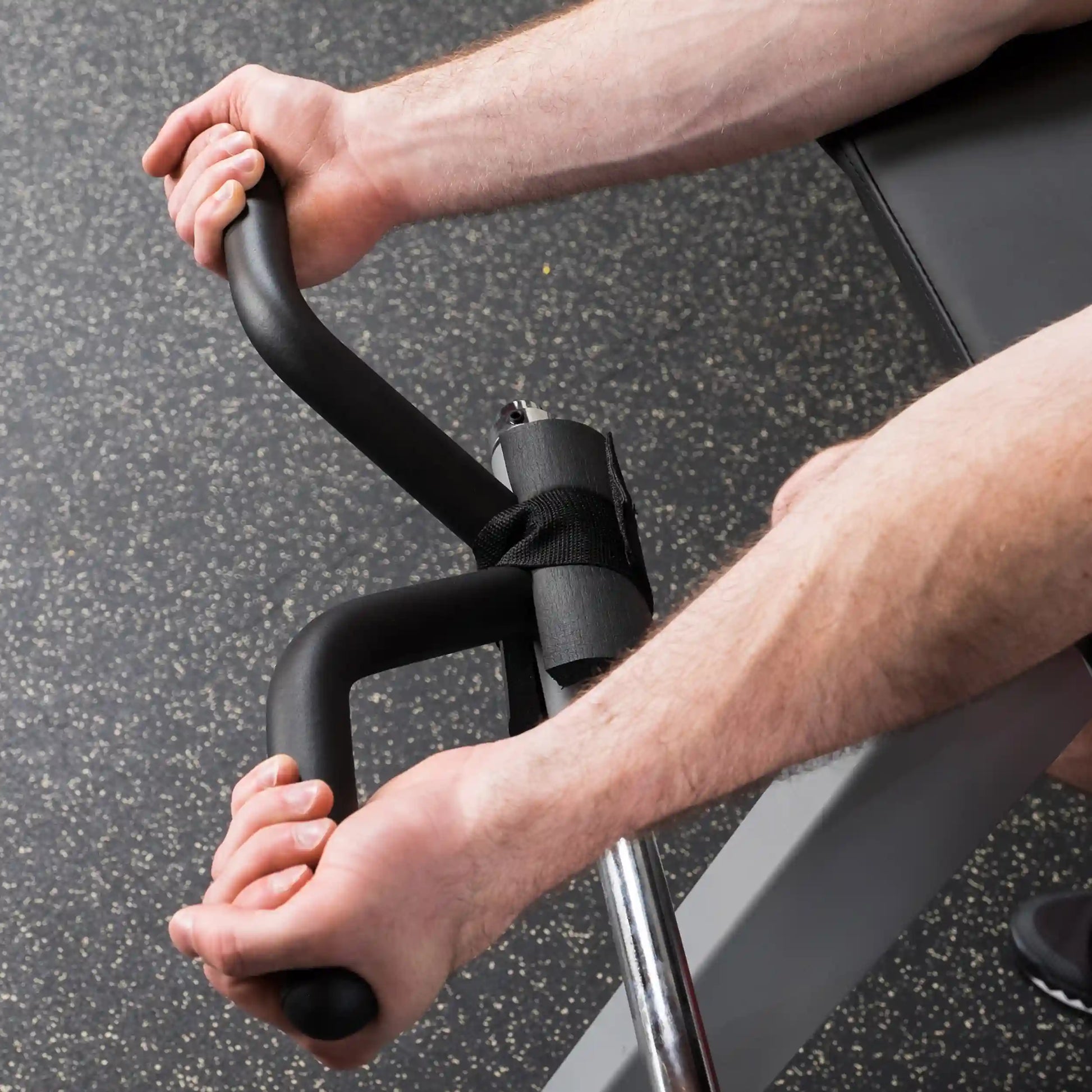 Man using black bicep isolator for weightlifting on gym floor.