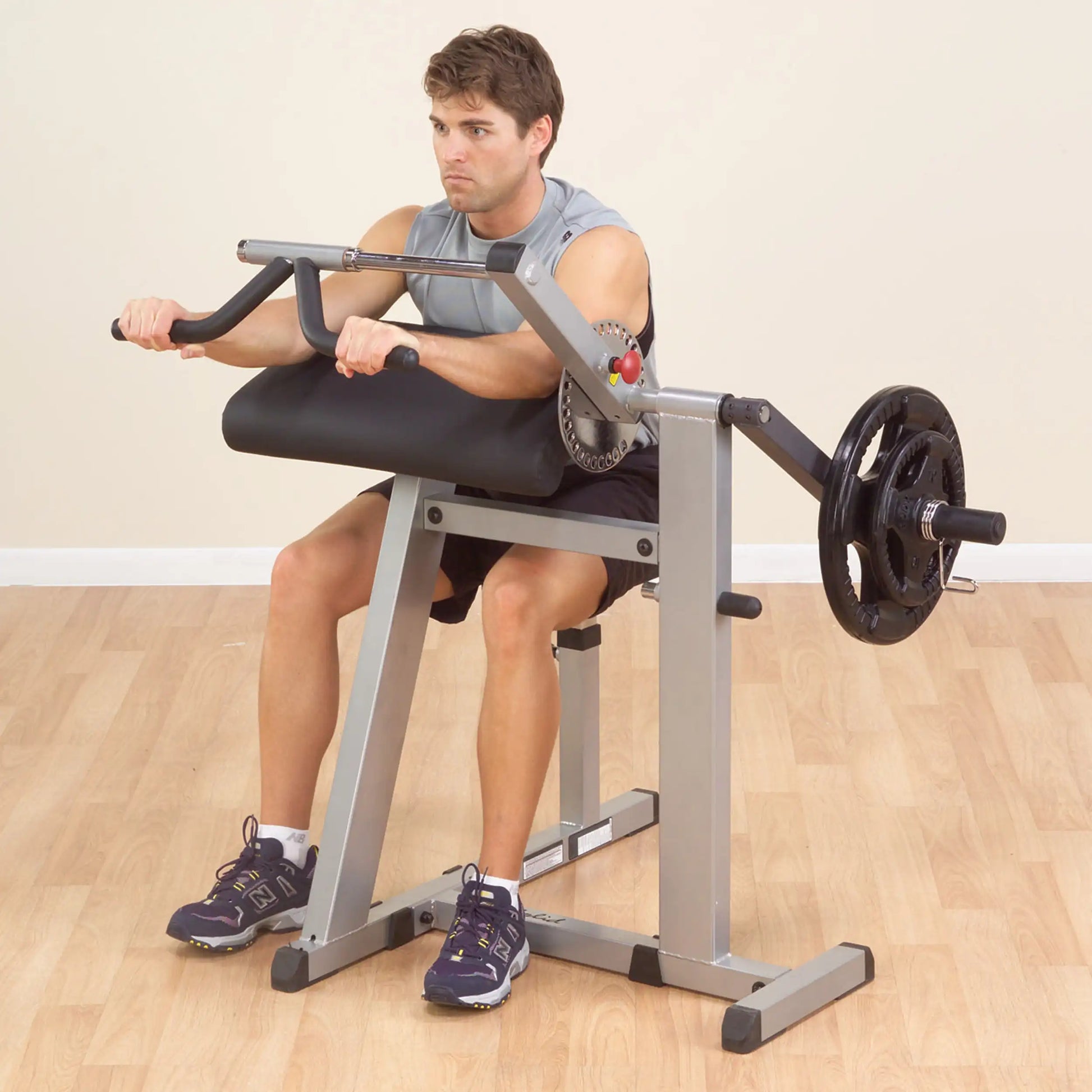 Man using a seated preacher curl machine for arm workout in a gym.