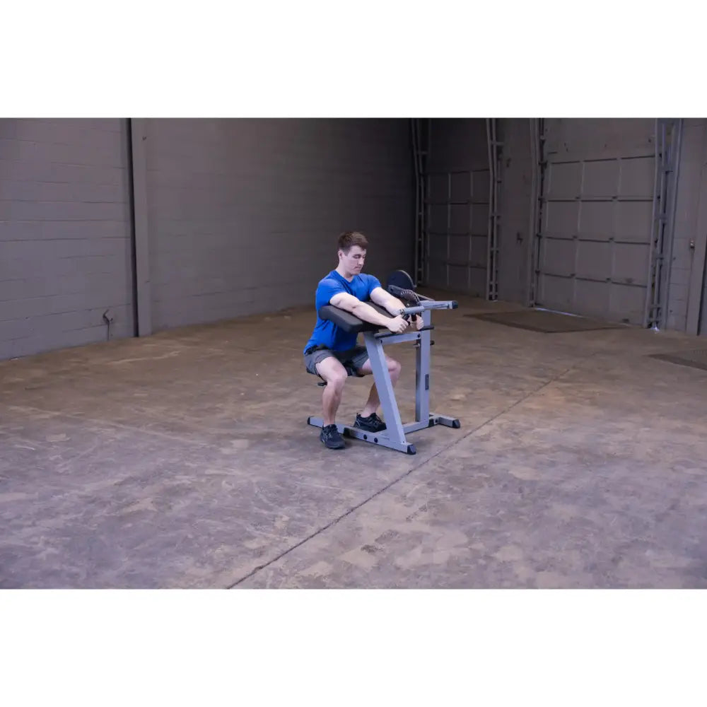 Man using seated calf raise machine in a gym.