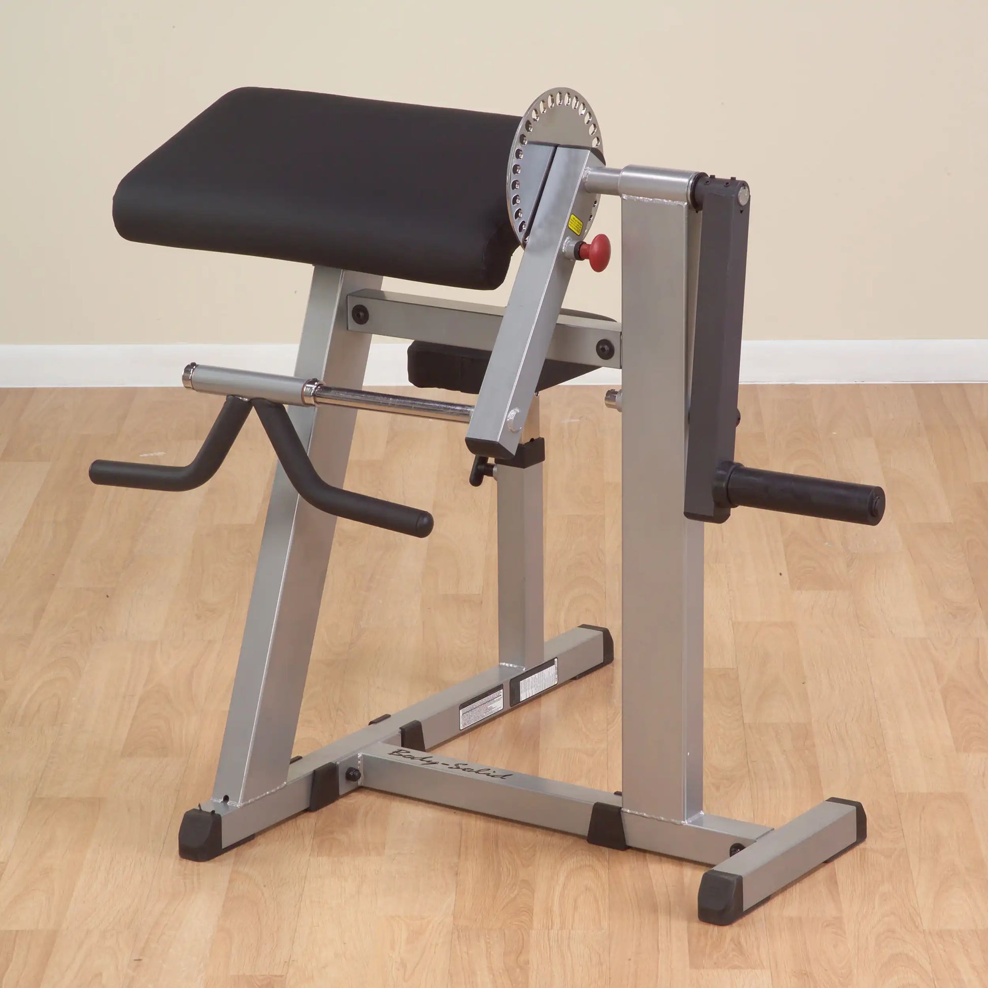 Body-Solid preacher curl bench with adjustable armrest on wooden floor.