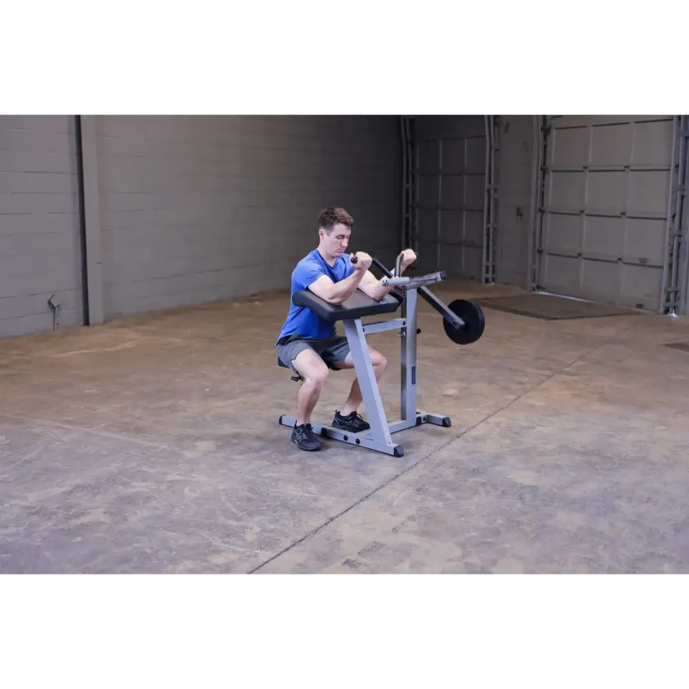 Man using a seated calf raise machine in a gym with concrete flooring.