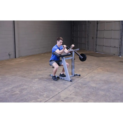 Man using a seated calf raise machine in a gym with concrete flooring.