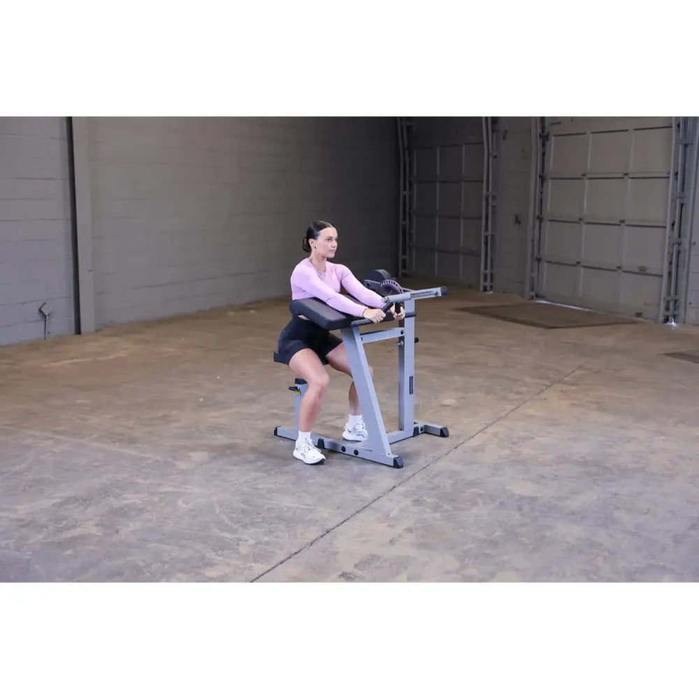 Woman using a seated calf raise machine in a gym.