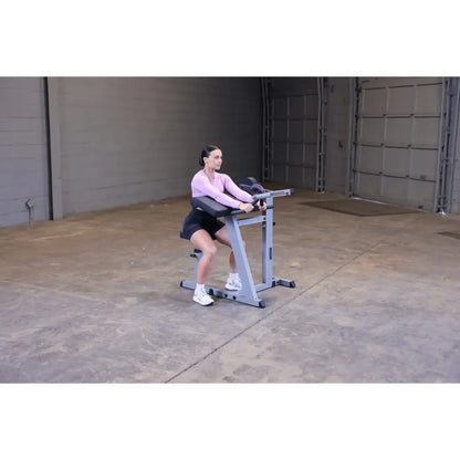 Woman using a seated calf raise machine in a gym.