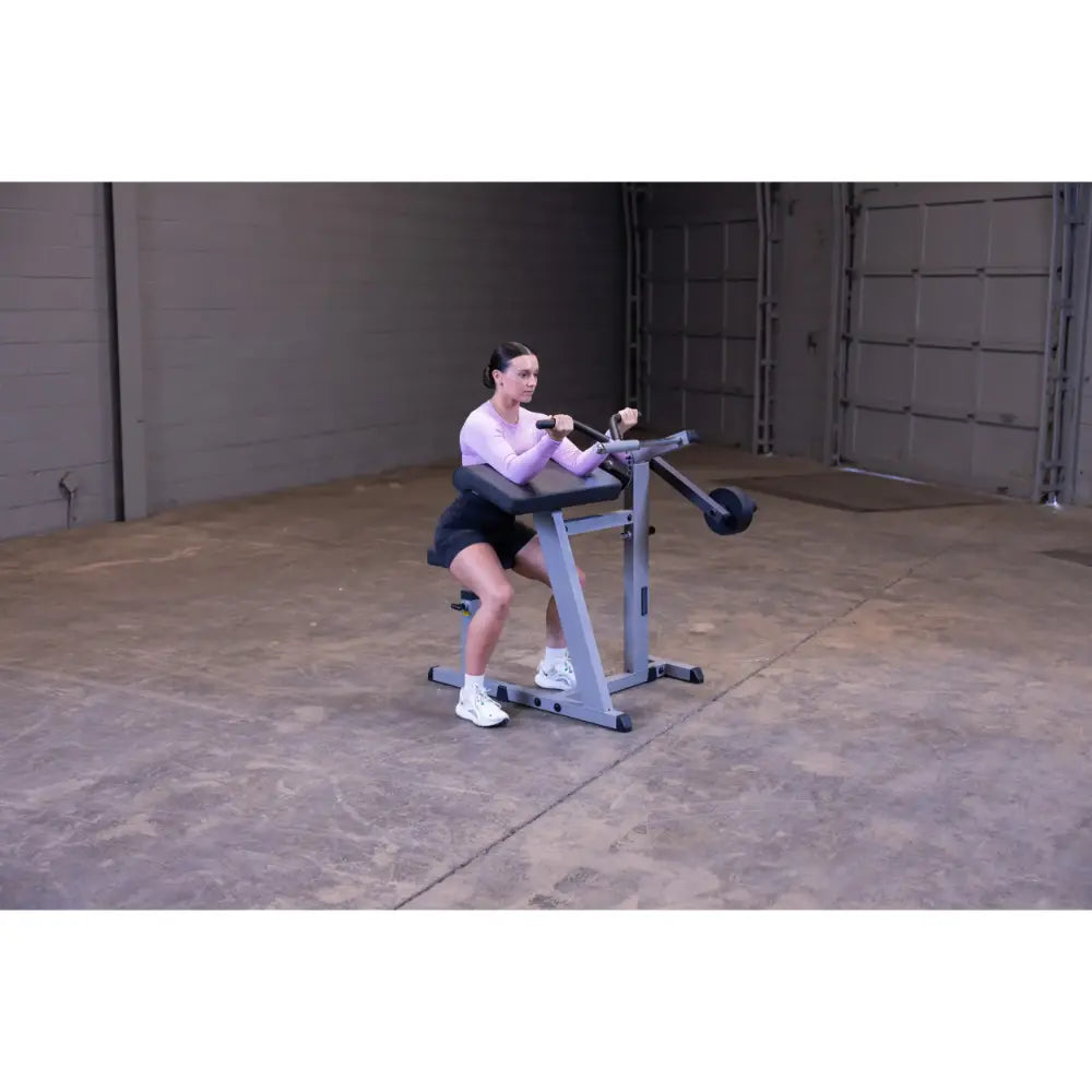 Woman using seated calf raise machine in a gym.