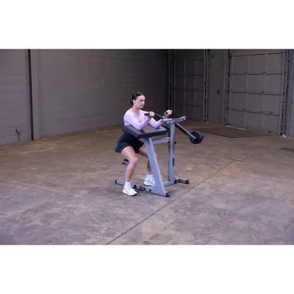 Woman using seated calf raise machine in a gym.