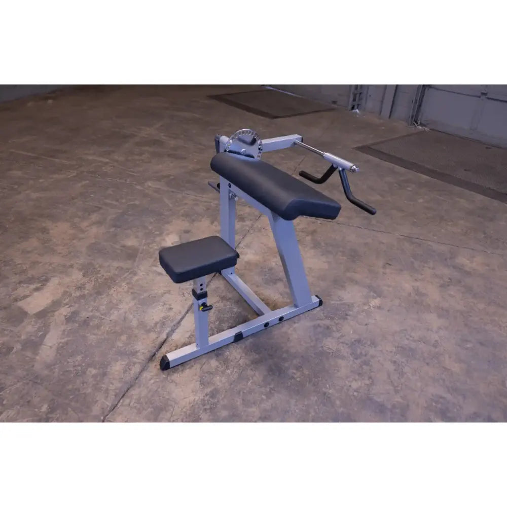 Preacher curl bench with adjustable seat and arm pad for bicep workouts in a gym setting.