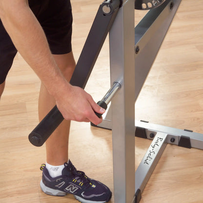 Man adjusting Body-Solid weight bench with black handle on wooden floor.