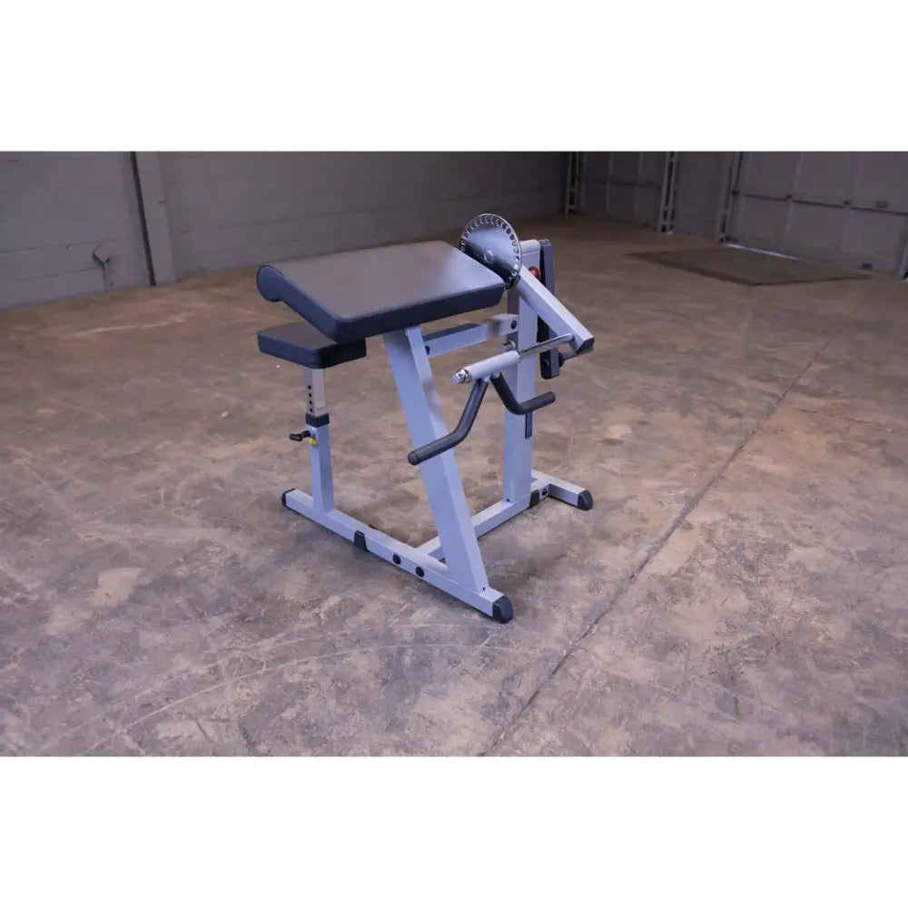Seated calf raise machine with padded seat and adjustable height in a gym setting.