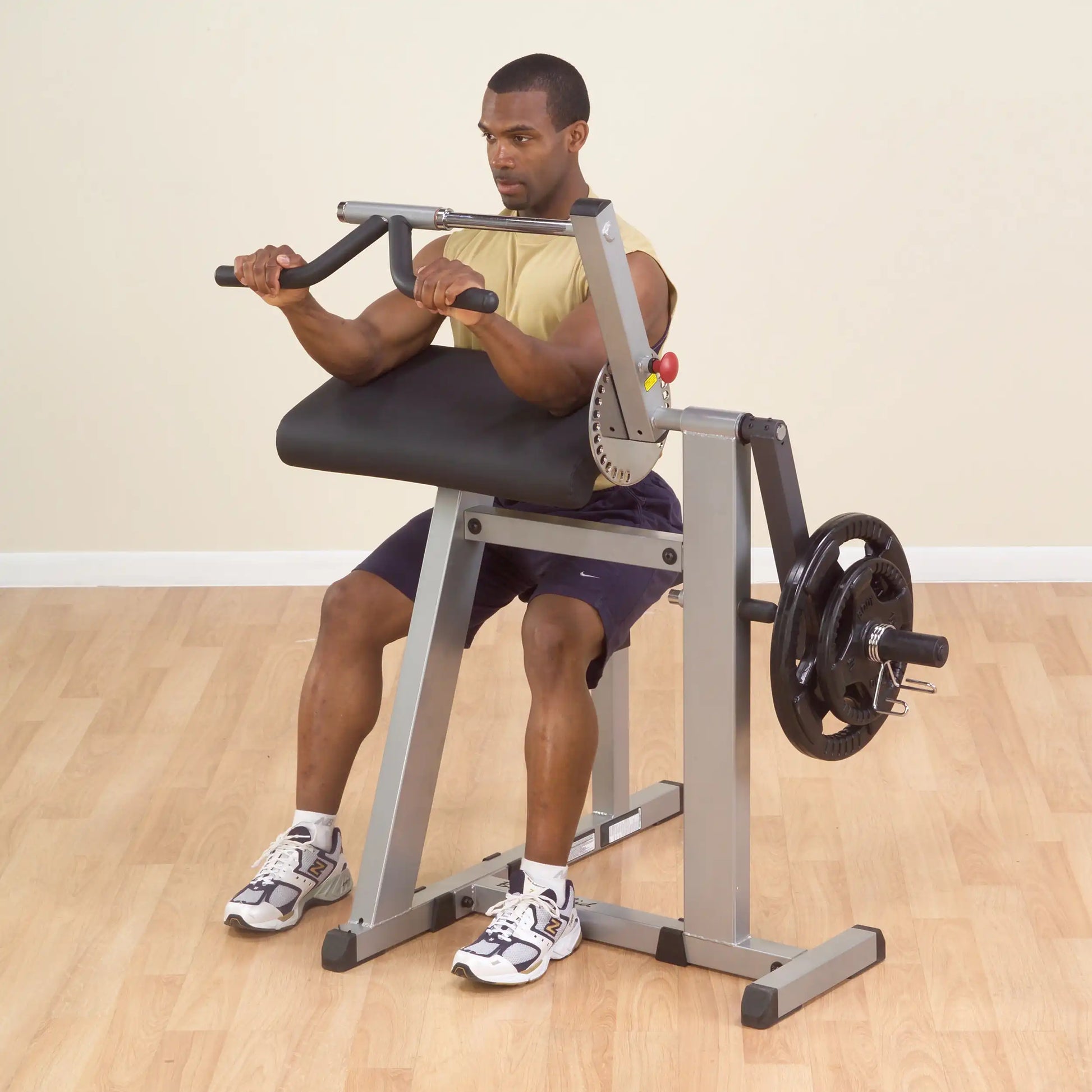 Man using bicep curl machine with black padded support in gym.