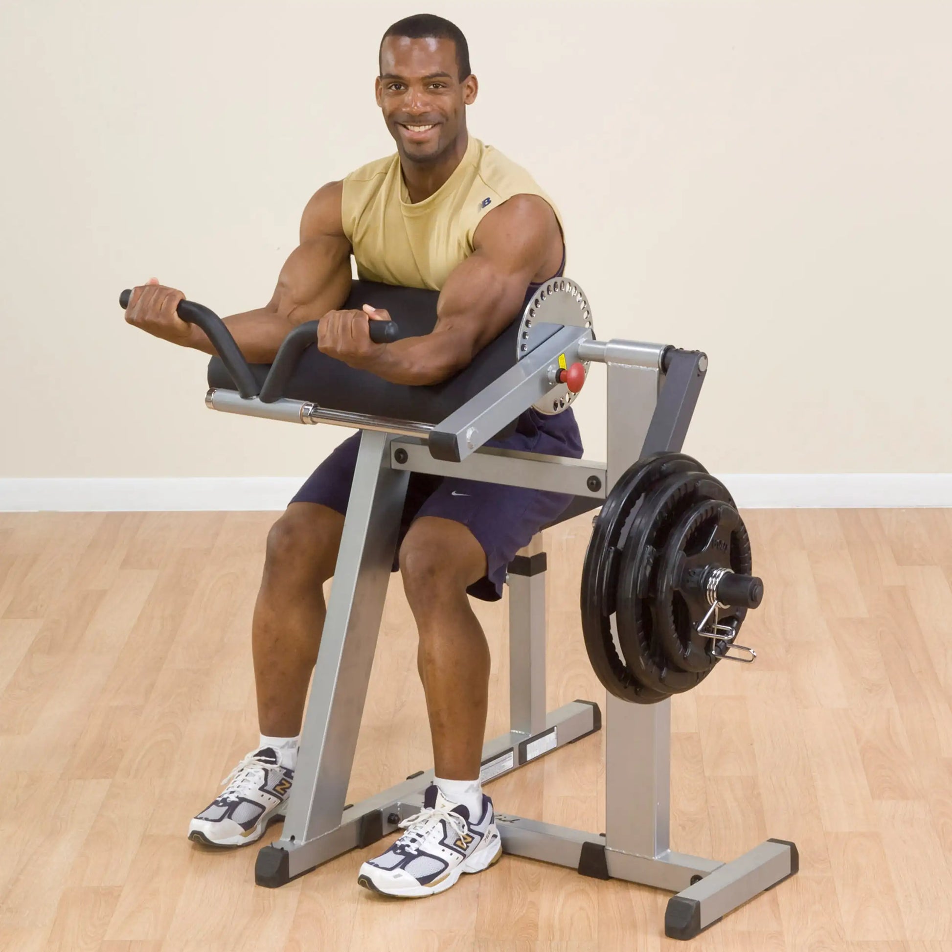 Man using a preacher curl machine with black padding for arm workouts.