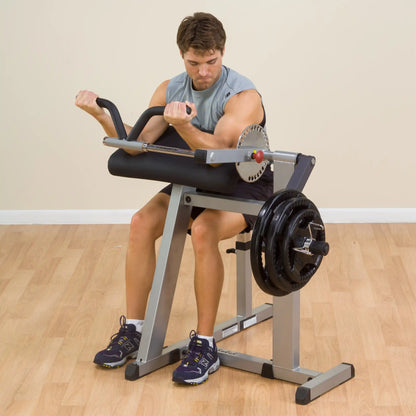 Man using a bicep curl machine with weight plates for strength training.