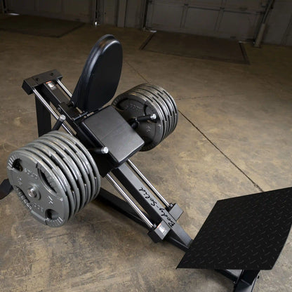 Body-Solid leg press machine with heavy weight plates on concrete floor.