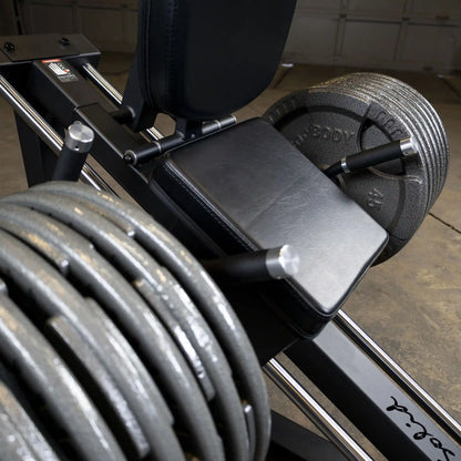 Leg press machine with stacked weights and black padded seat for strength training.