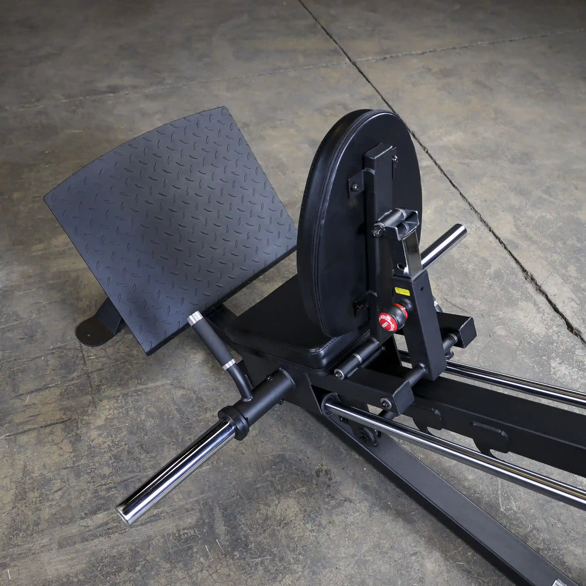 vertical leg press with black steel frame on concrete floor.