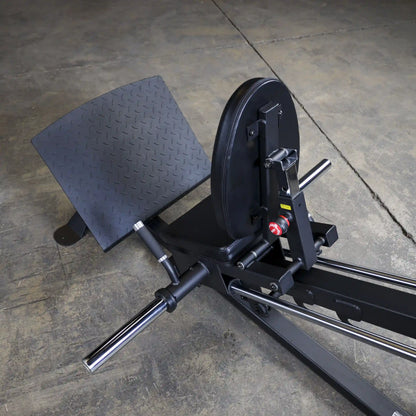 vertical leg press with black steel frame on concrete floor.