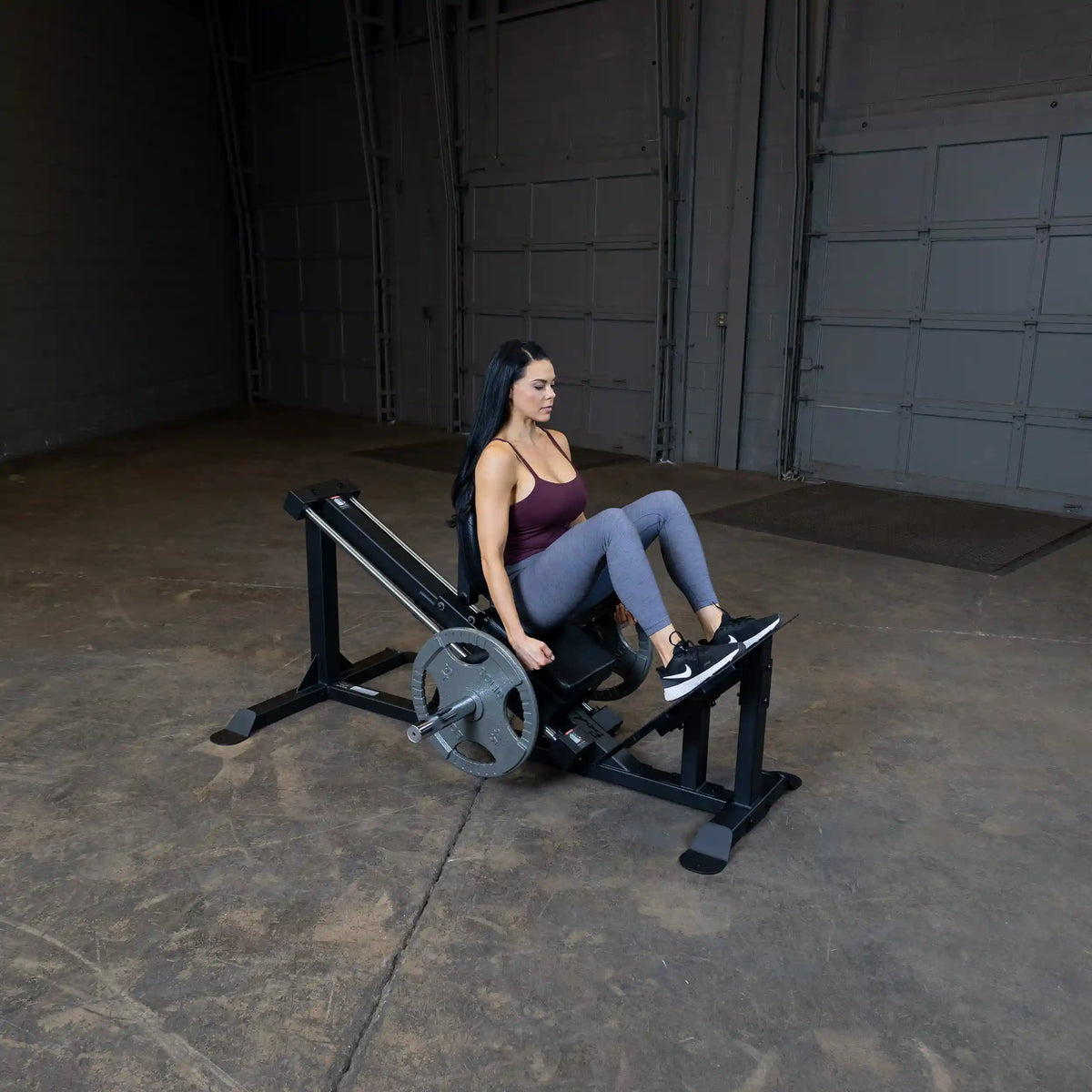 Woman using a leg press machine for strength training in a gym.