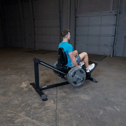Man in blue shirt using a leg press machine with multiple weight plates in a gym.