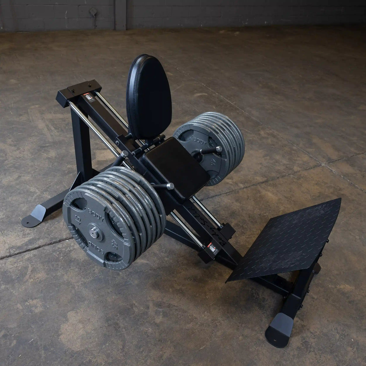 Leg press machine with black padded seat and multiple weight plates for strength training.
