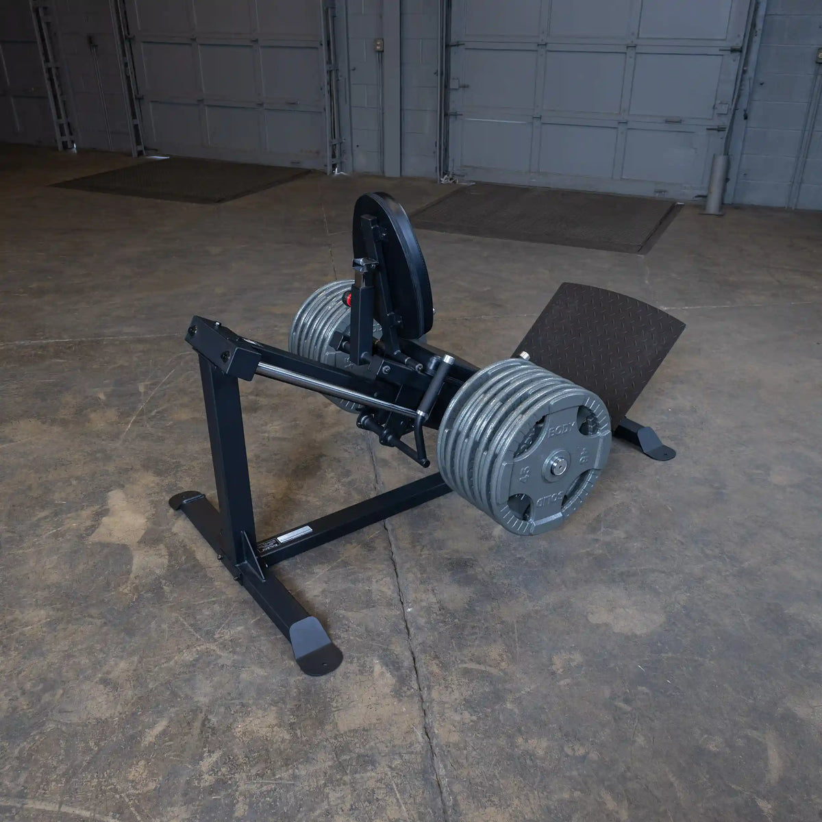 Leg press machine with weighted plates in an industrial gym setting.