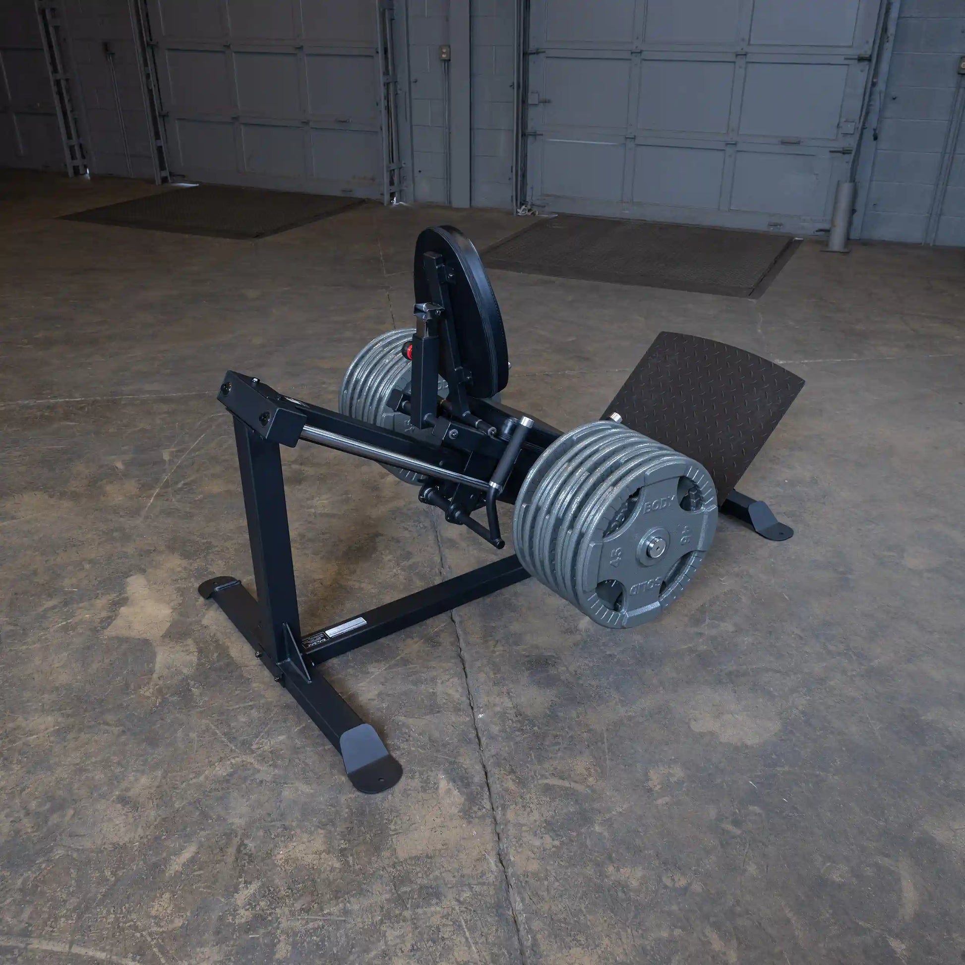 Leg press machine with weighted plates in an industrial gym setting.