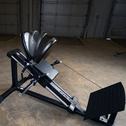 Rogue ISO Leg Press in black with adjustable seat and footplate in a warehouse gym.