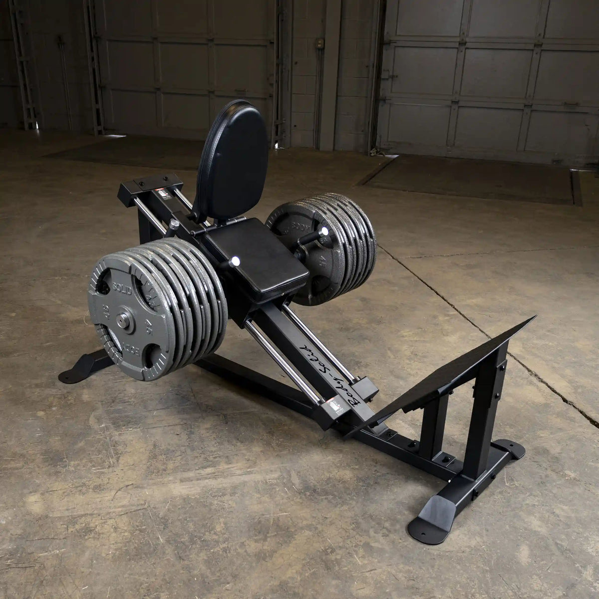 Leg press machine with adjustable weights in a garage gym setting.