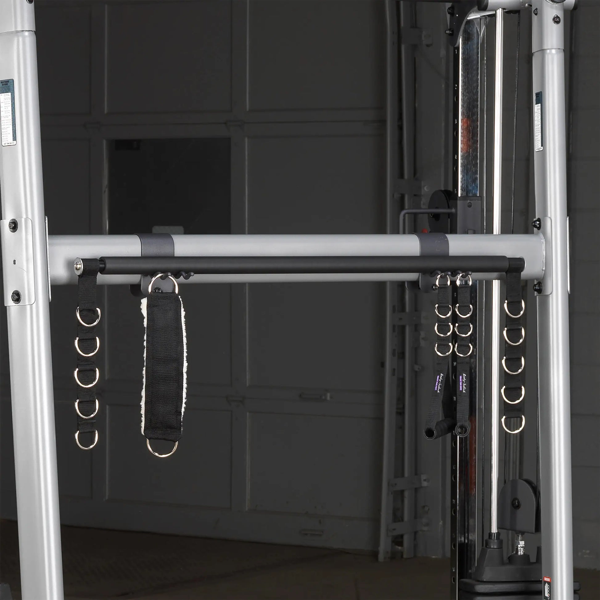 Dual cable cross machine with multiple D-rings and padded strap for versatile workouts.
