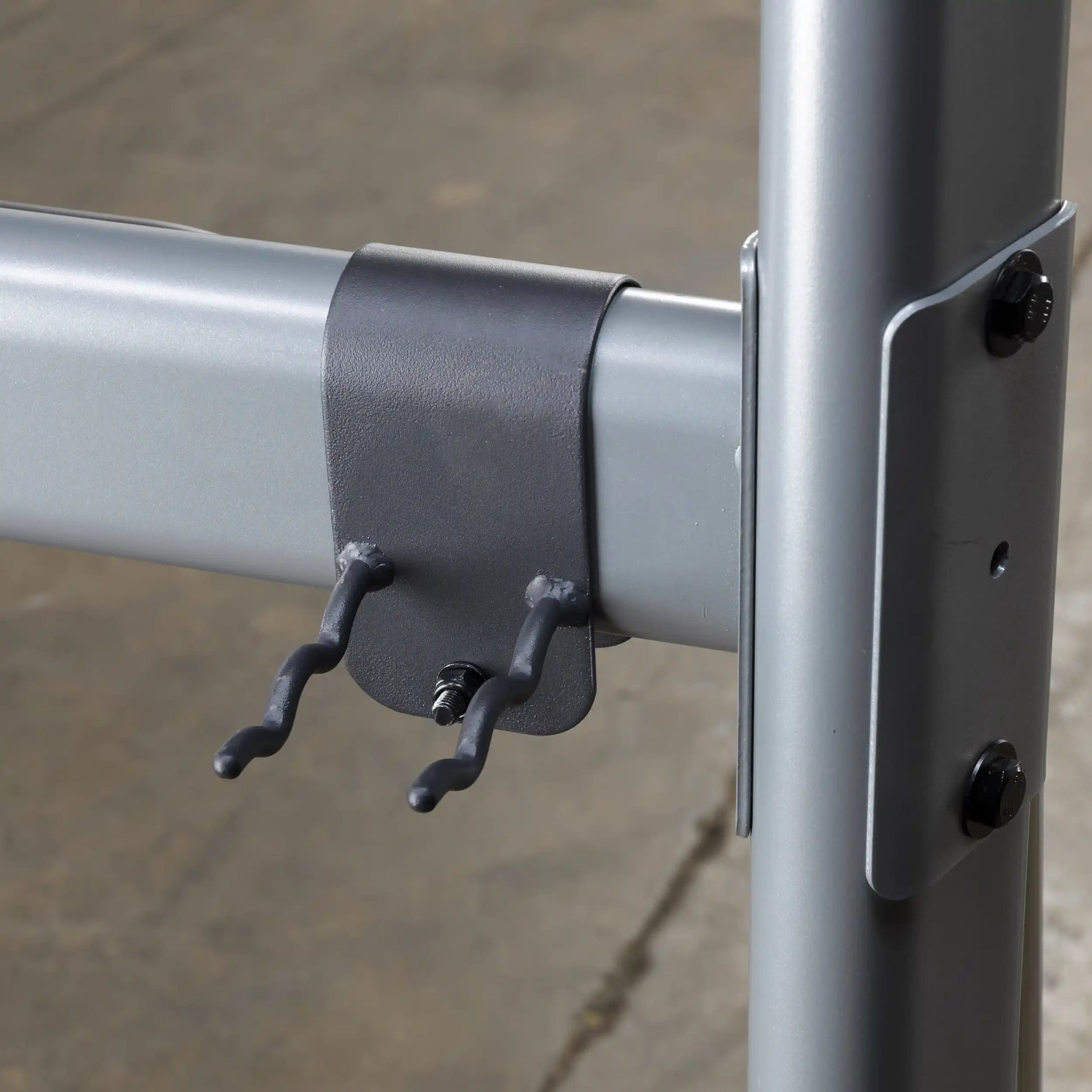 Gray metal clamp with two hooks on a steel frame, ideal for industrial shelving support.