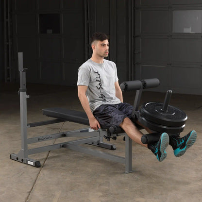 Man using Body-Solid weight bench for leg exercises in a garage gym.