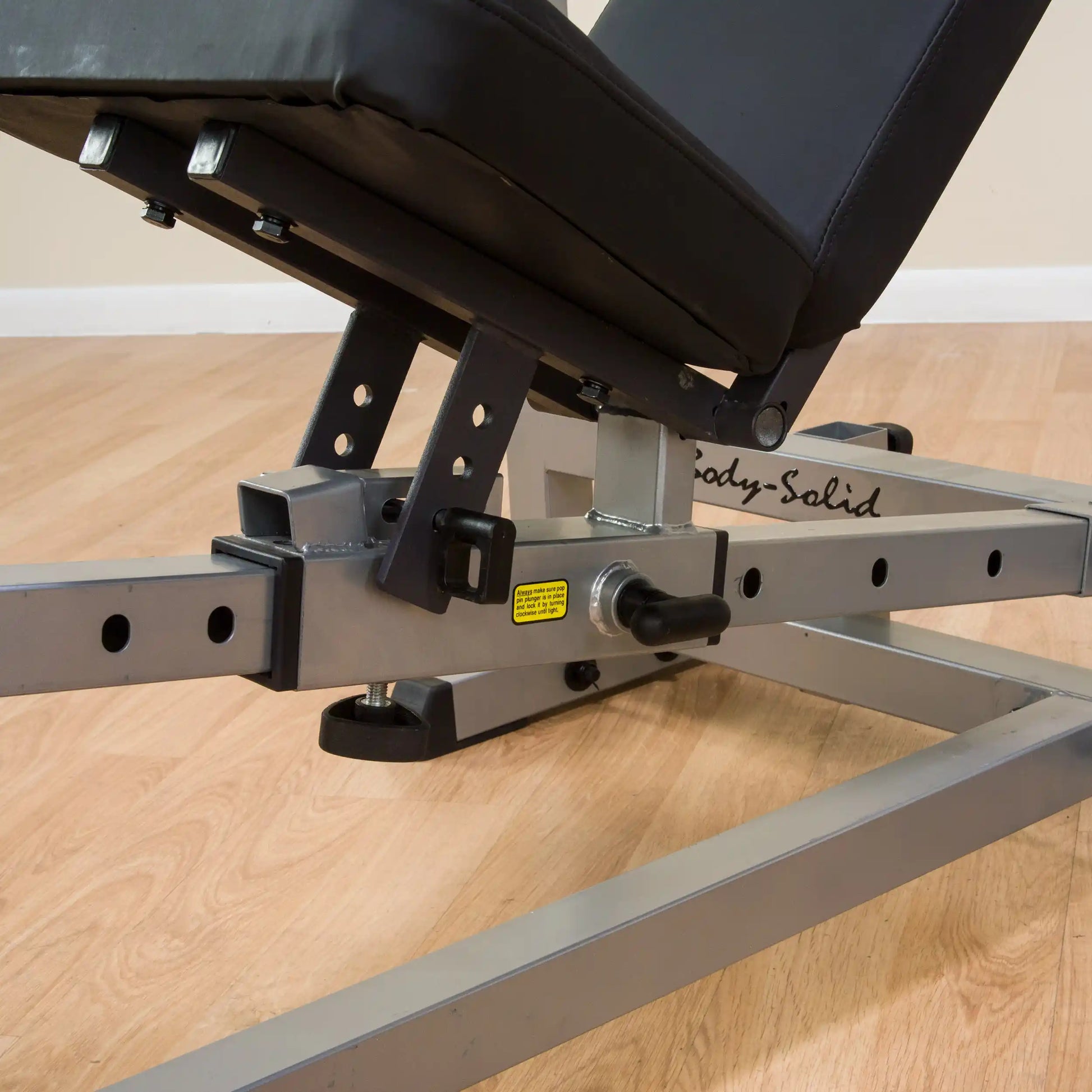 Body-Solid adjustable weight bench with black padding on wood floor.