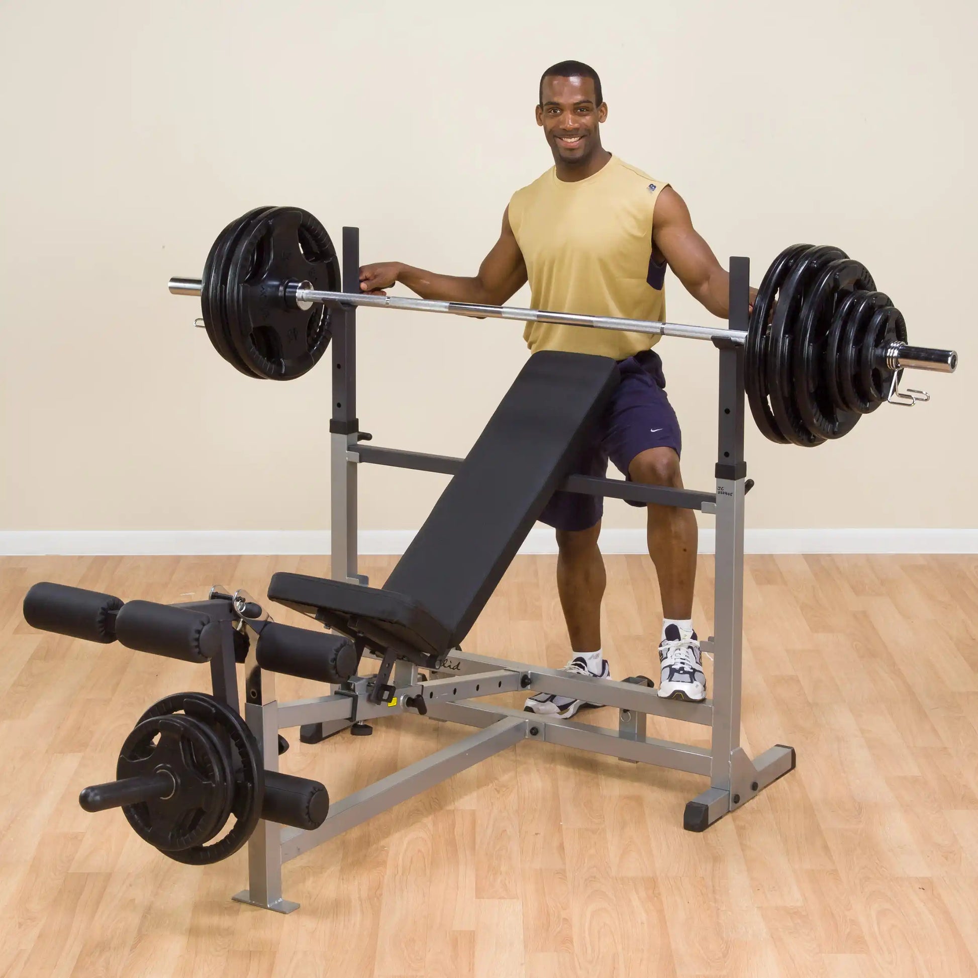 Man using adjustable weight bench for barbell exercises.
