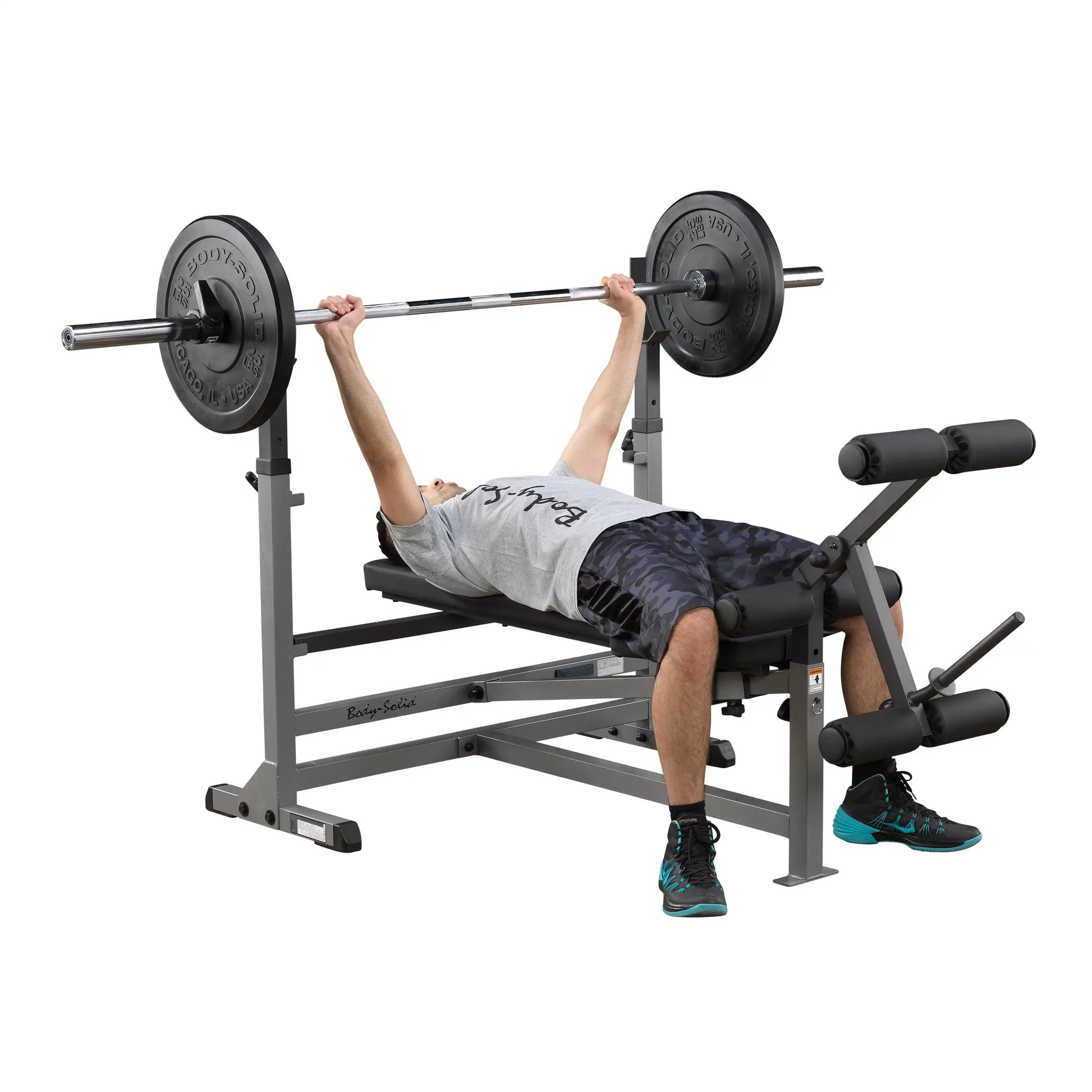 Man lifting weights on Body-Solid bench press with black weight plates.