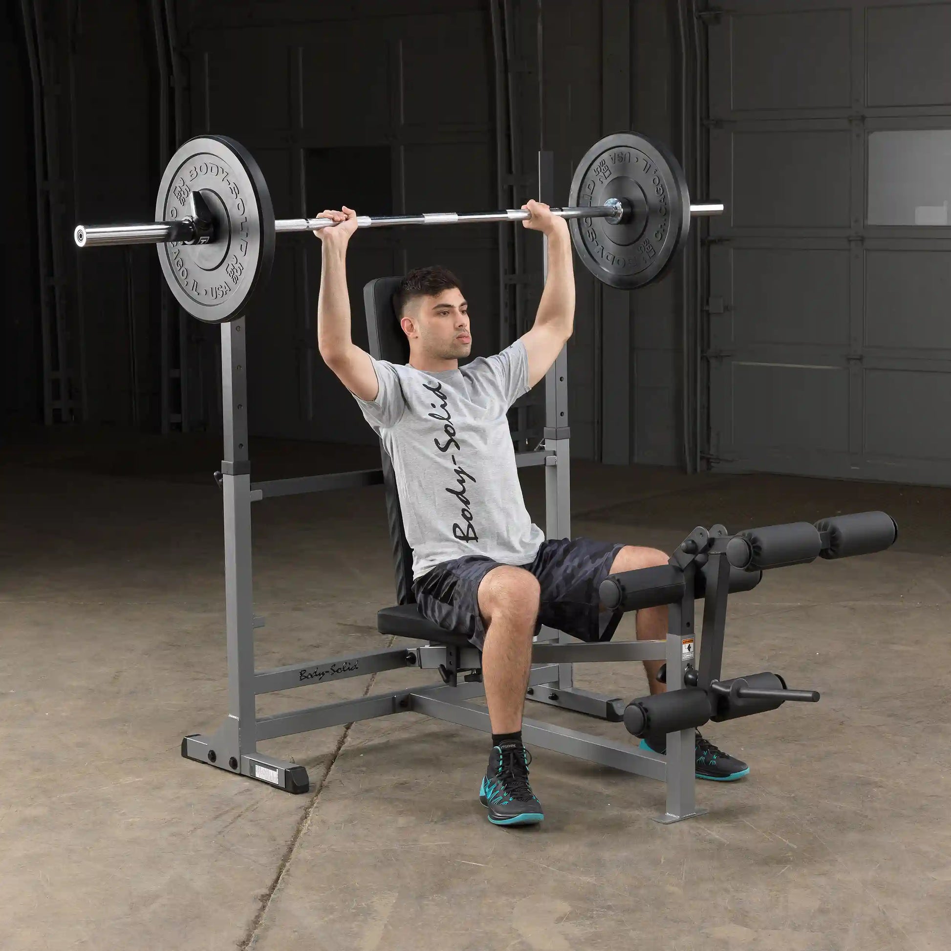 Body-Solid weight bench with man lifting barbell in gray t-shirt, showcasing home gym equipment.