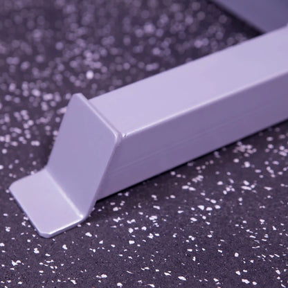 Gray metal squat rack foot on speckled gym floor.
