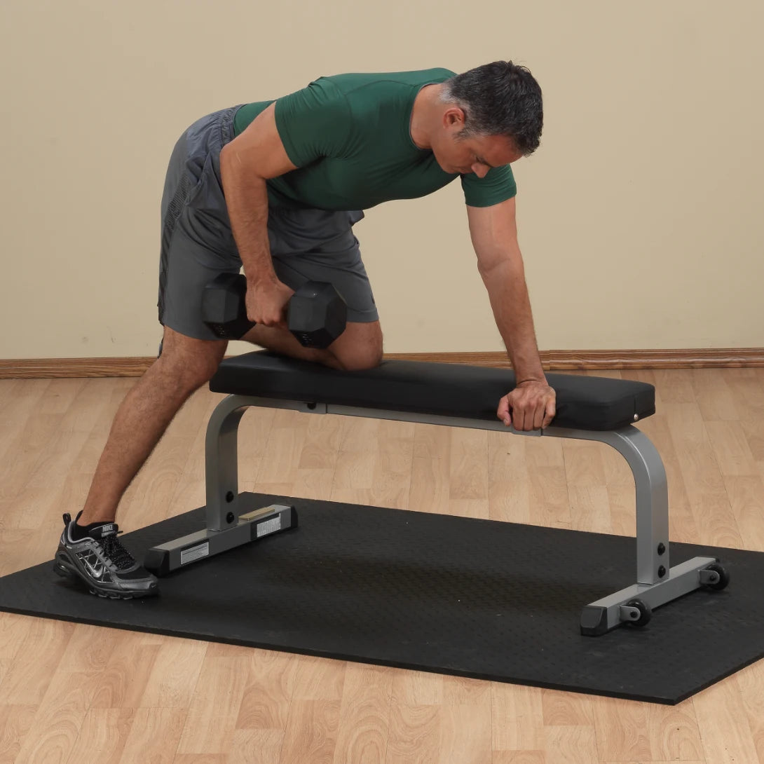 Man performing dumbbell row on black workout bench.