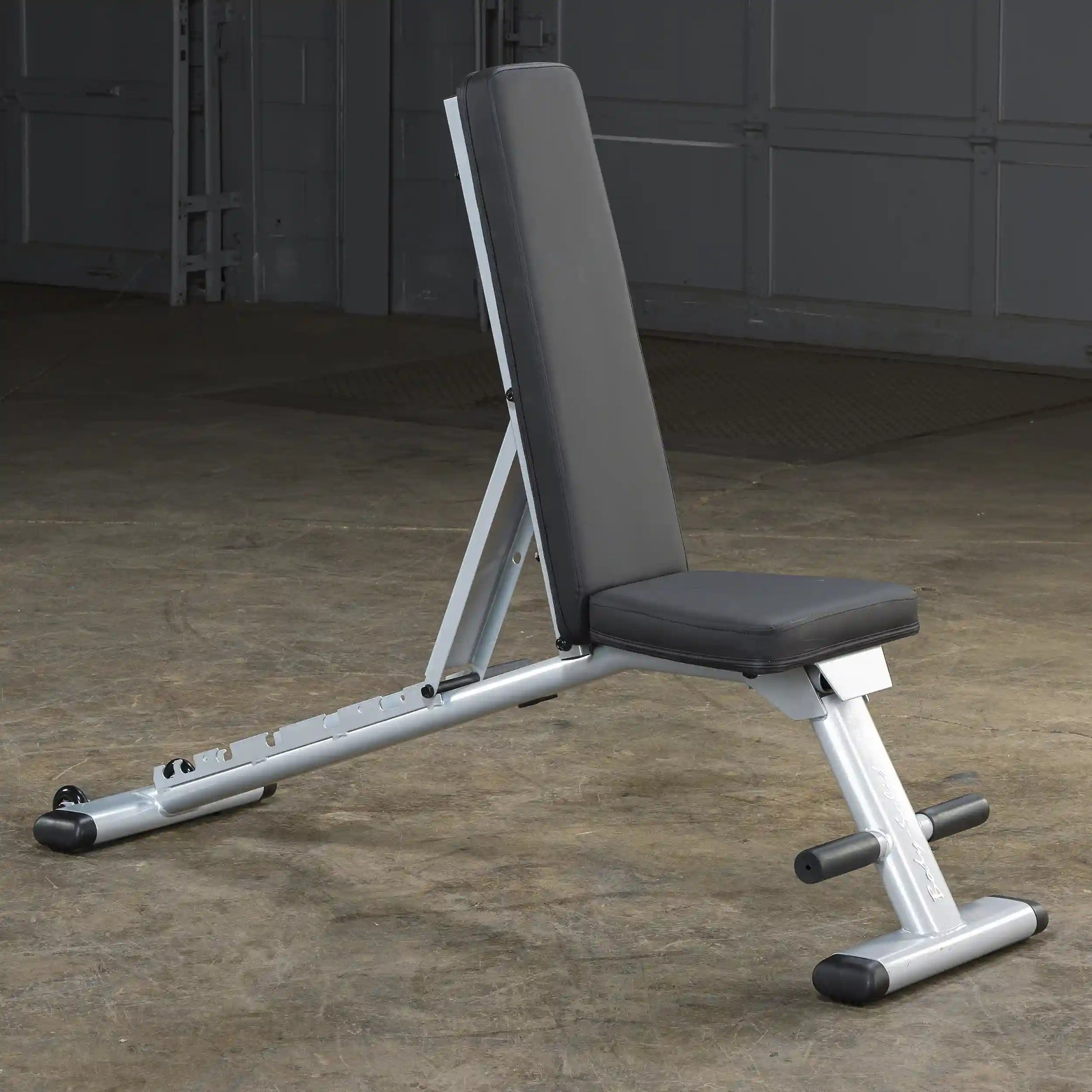 Adjustable weight bench with black padding in a gym setting.