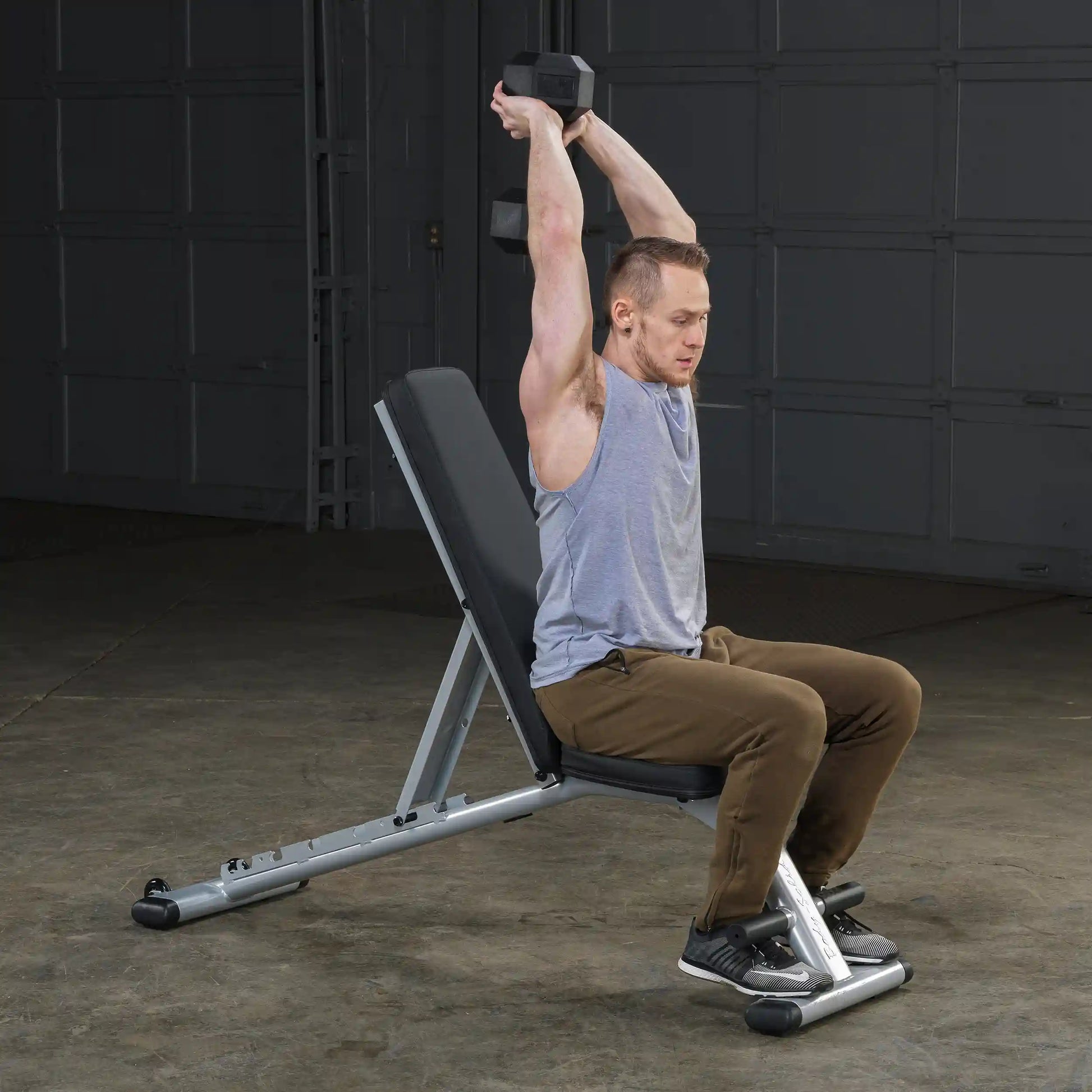 Man performing seated dumbbell tricep extension on adjustable weight bench.