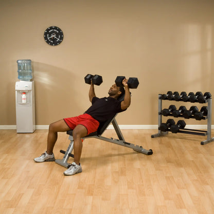 Man in red shorts lifting dumbbells on incline bench in gym.