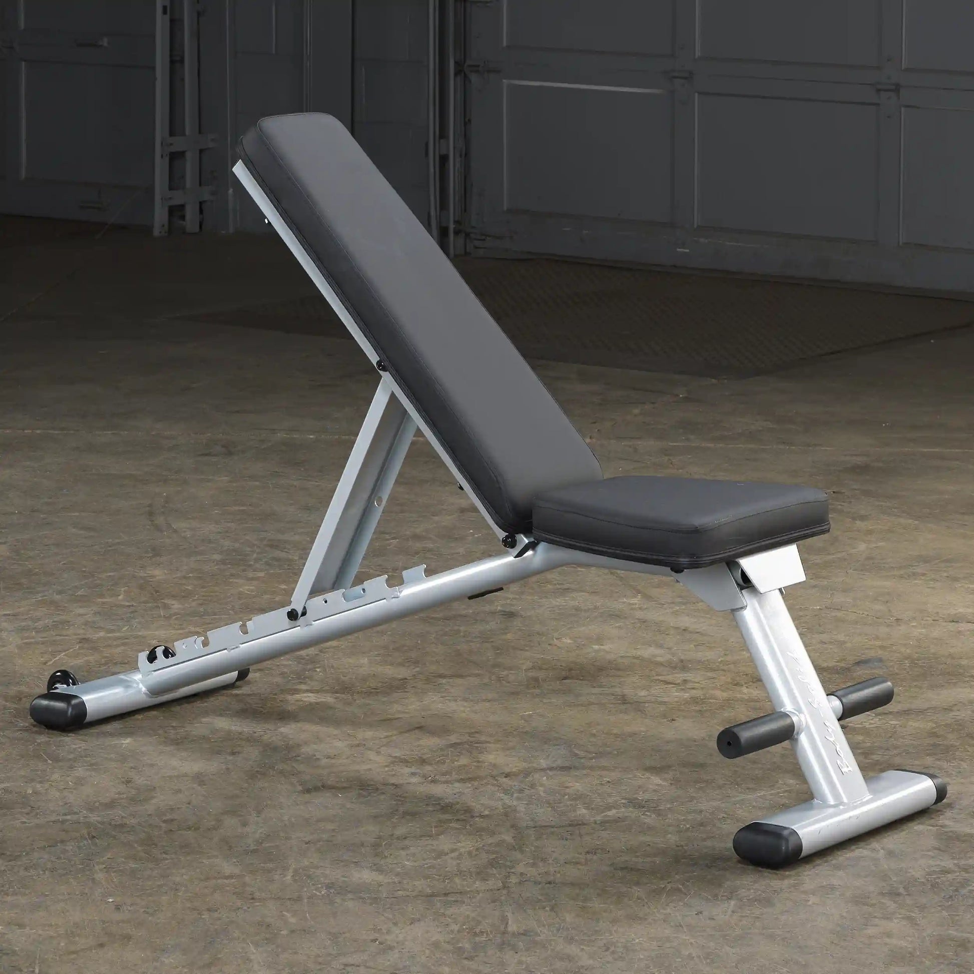 Adjustable weight bench with black padding and silver frame in a gym setting.