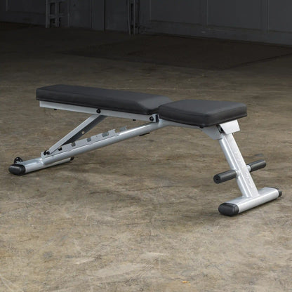 Adjustable weight bench with silver frame and black padding on a concrete floor.