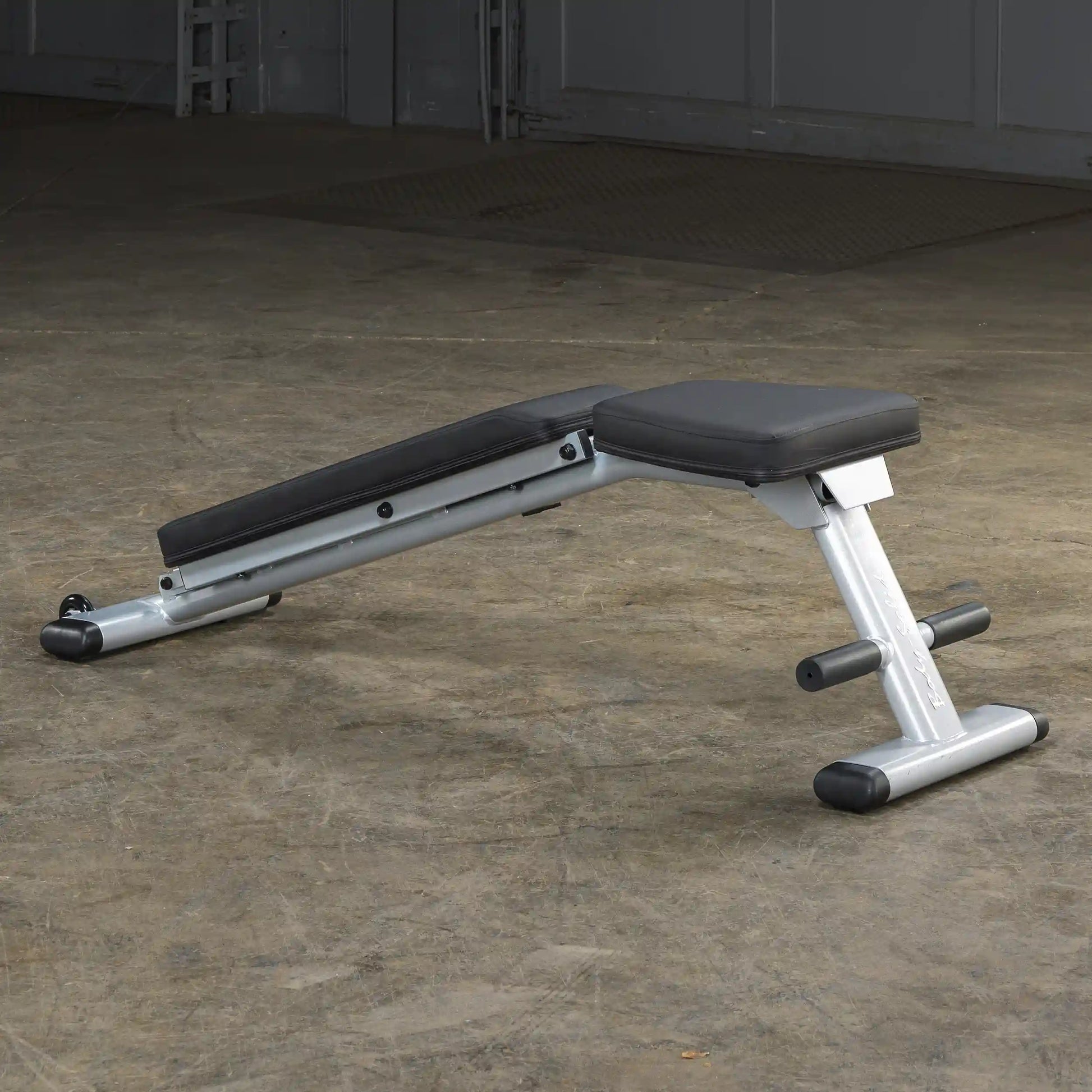 Adjustable weight bench with black padding on a concrete floor.
