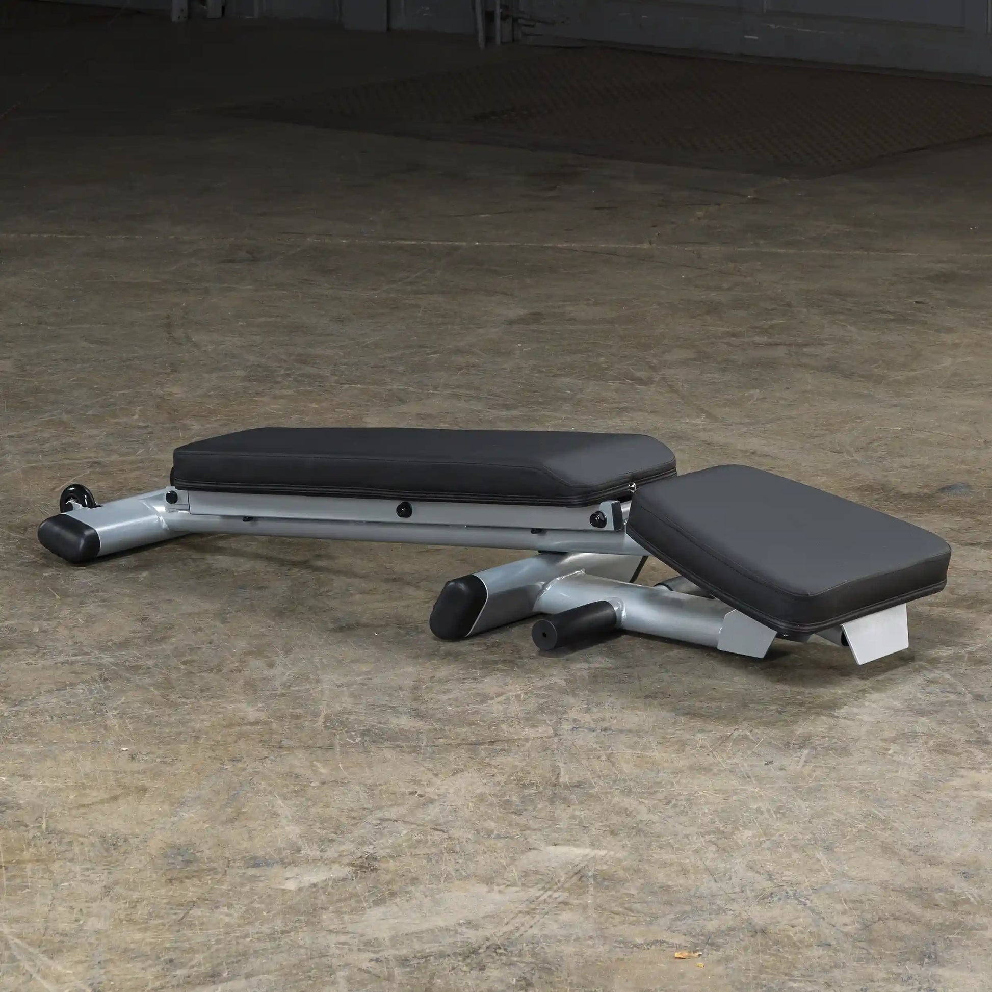 Adjustable weight bench with black padding on a concrete floor, ideal for home gym setups.