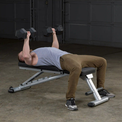 Man lifting dumbbells on adjustable weight bench in gym.